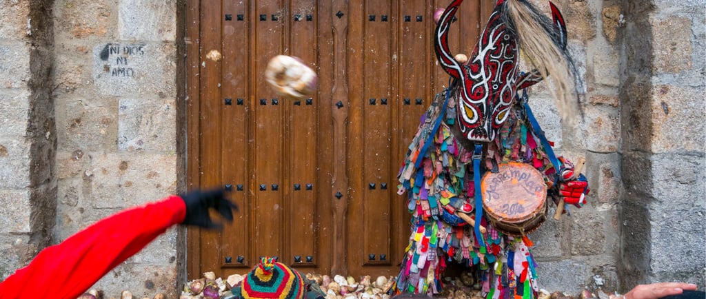 People throwing turnips at Jarramplas wearing a colorful masked costume during a Spanish festival.