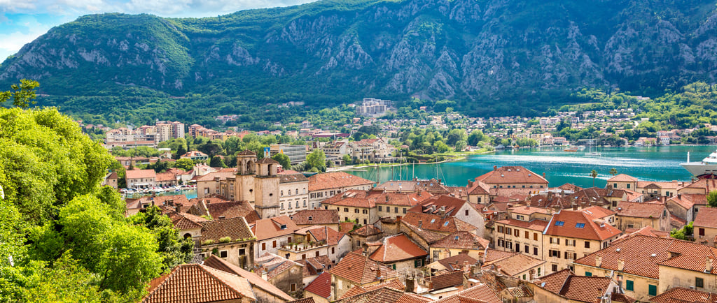 Panoramic view of the red tile roofs in the historic Old Town of Kotor, Montenegro, nestled against lush green mountains and