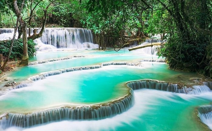 Kuang Si Falls features multi-tiered turquoise limestone pools and cascading waterfalls in a lush tropical jungle.