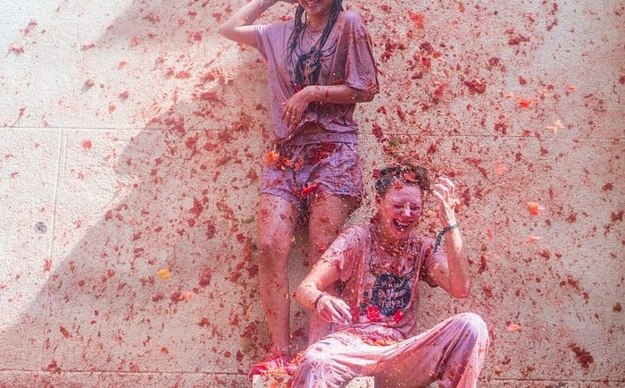 Two people laughing and covered in pulp during the La Tomatina tomato food fight festival in Spain.