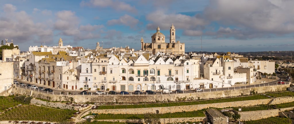 Aerial view of Locorotondo, Puglia, featuring white houses and the San Giorgio Church in Italy.