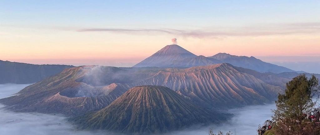 Sunrise view of Mount Bromo and Mount Semeru volcanoes rising above morning mist in Indonesia.