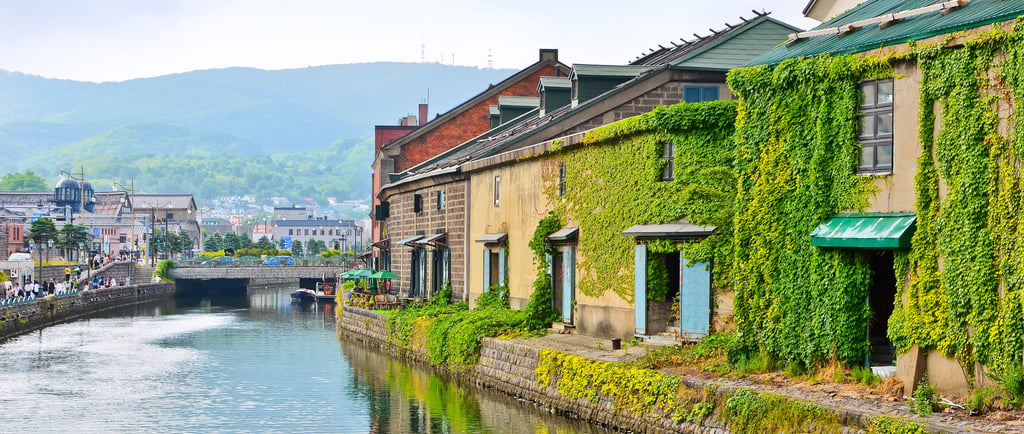 Historic ivy-covered stone warehouses along the scenic Otaru Canal in Hokkaido, Japan.