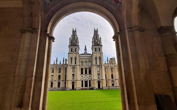 A view of the Gothic twin towers at All Souls College, Oxford University, framed by a stone archway.