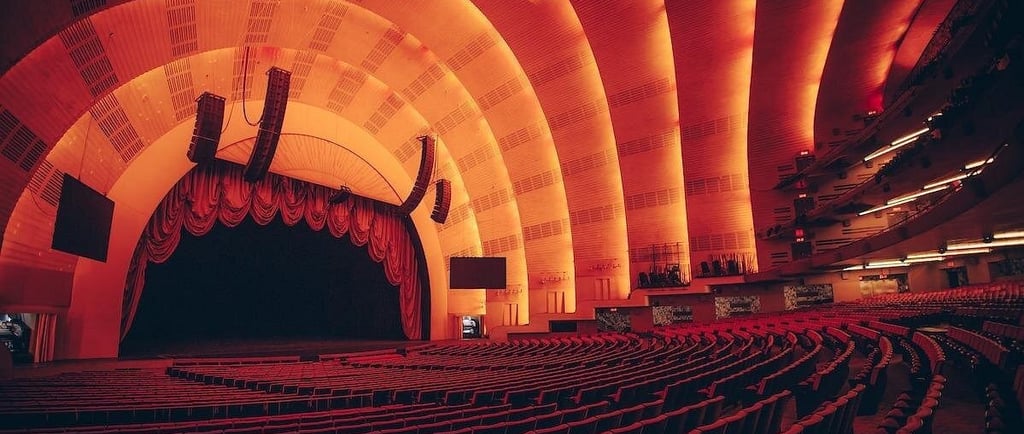 Interior of Radio City Music Hall stage and red seating with Art Deco arched ceiling.