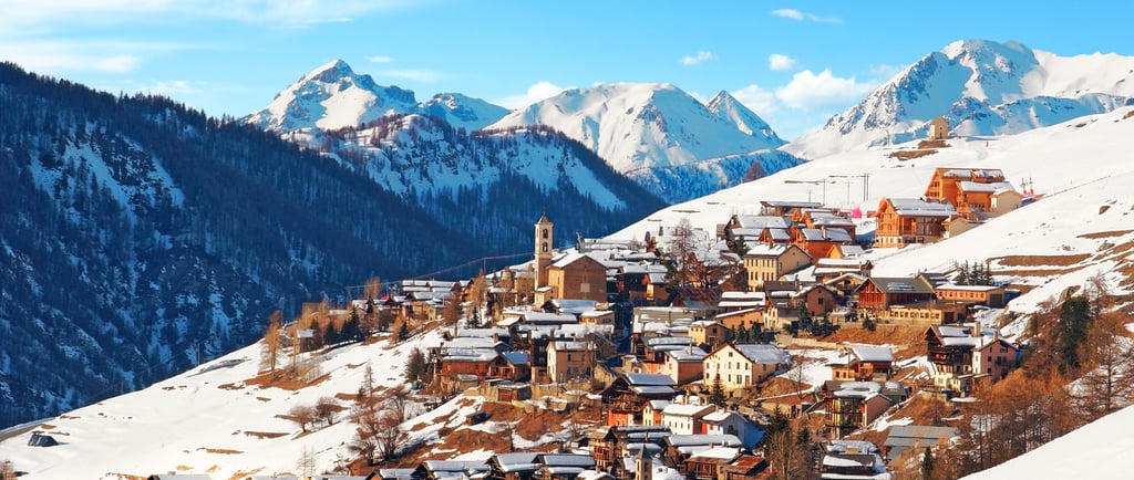 Panoramic view of a snow-covered alpine village nestled in the French Alps with scenic mountain peaks.