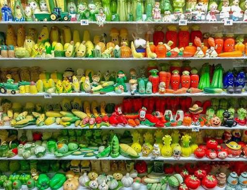 Collection of colorful vintage vegetable salt and pepper shakers organized on shelves.