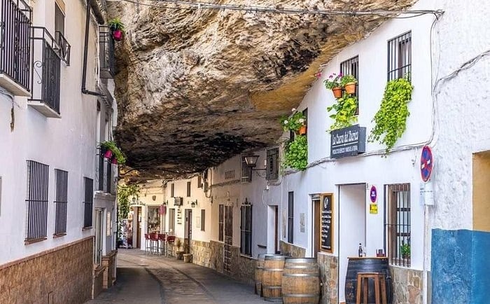 White houses built into a massive rock overhang in Setenil de las Bodegas, Spain.