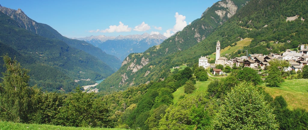 Panoramic view of a scenic mountain village in the Swiss Alps with a historic stone church.