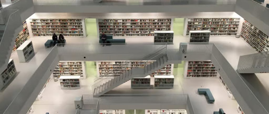 Modern white minimalist library interior with multiple floors, stairs, and book-filled shelves.