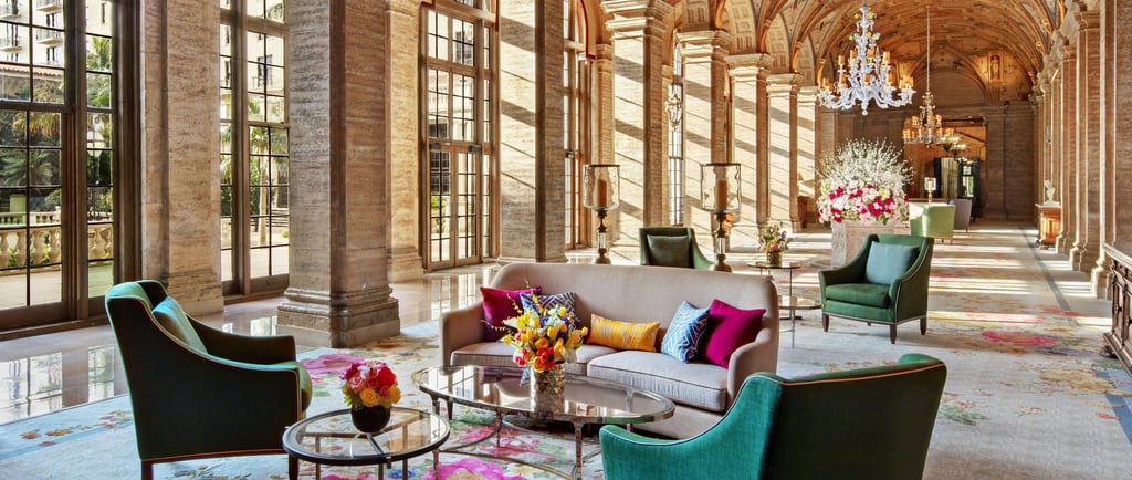Elegant hotel lobby with vaulted ceilings, crystal chandeliers, and colorful floral carpets.
