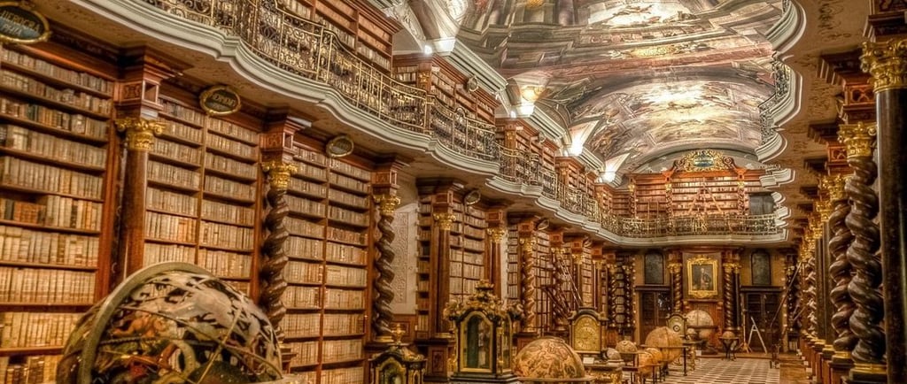 The historic Baroque Klementinum library in Prague featuring ornate bookshelves and ceiling frescoes.