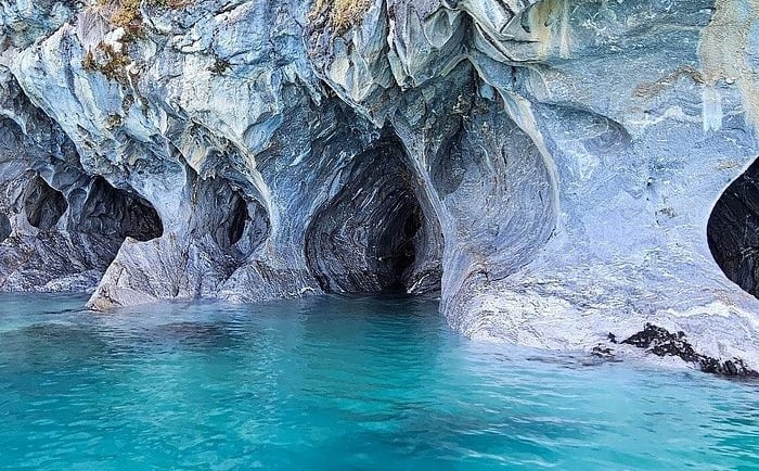 The Marble Caves in Patagonia featuring swirling blue rock patterns over turquoise glacial water.