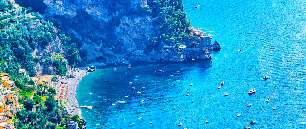 Aerial view of boats in the turquoise water of the Amalfi Coast near Positano beach in Italy.