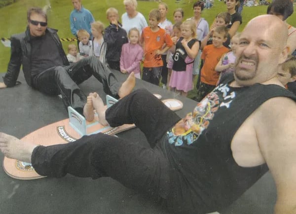 Two men compete in a competitive toe wrestling match on a platform in front of a crowd of spectators.
