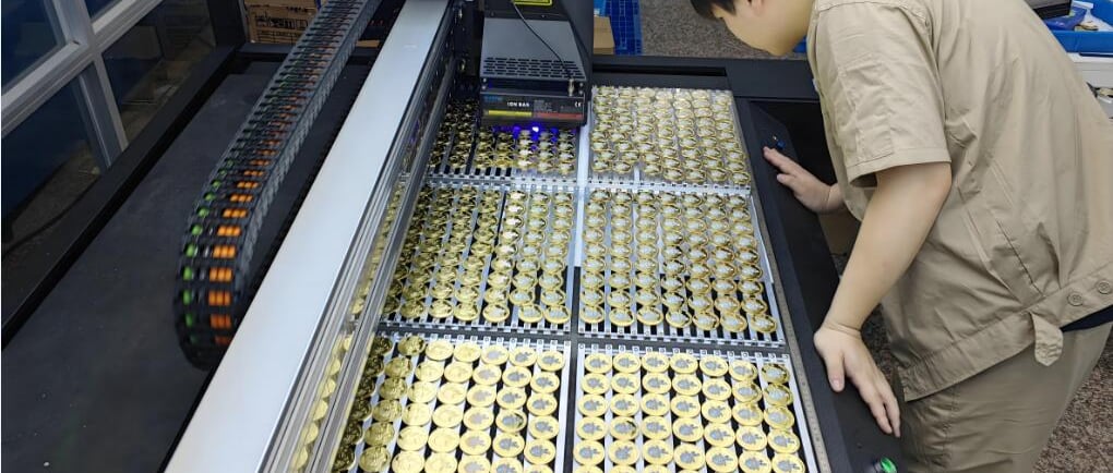 The worker is inspecting at a tray of enamel pins