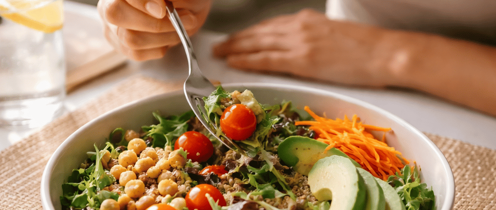 Mulher comendo salada de forma consciente à mesa, representando atenção alimentar e a prática de com