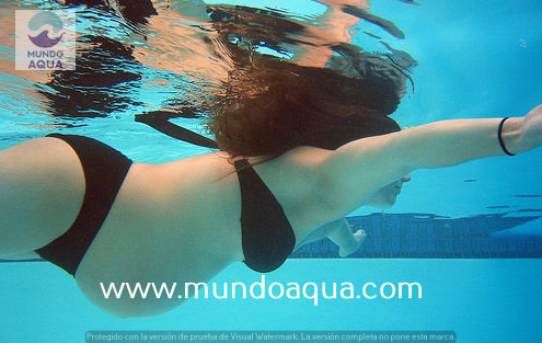 a woman in a bikini top swimming in a pool
