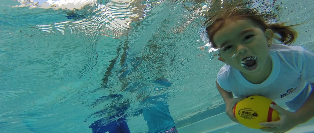 a young girl is playing with a ball in the water