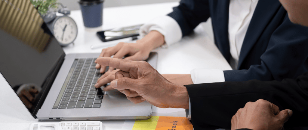a man and woman sitting at a desk with a laptop