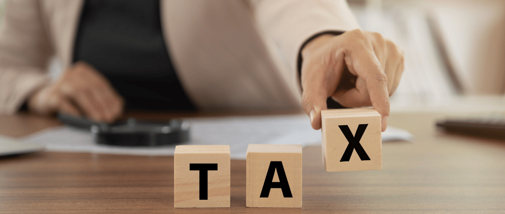 a woman is holding a wooden block with the word tax tax written on it