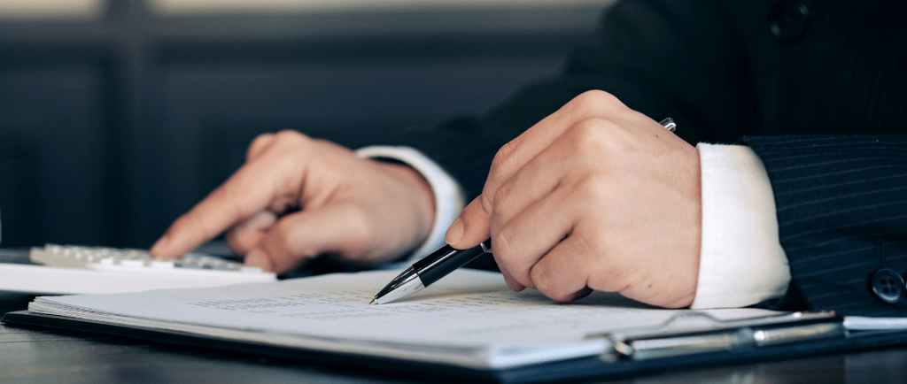 a person in a suit and tie is writing on a notebook