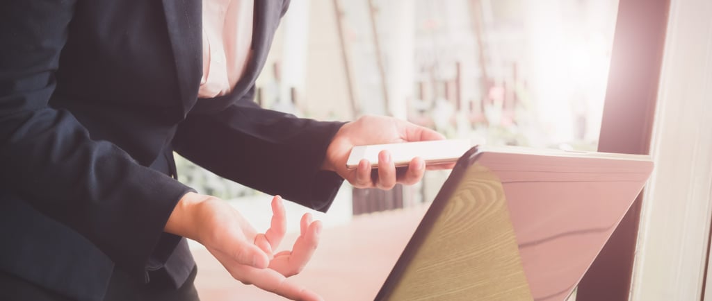 suit holding phone looking at computer