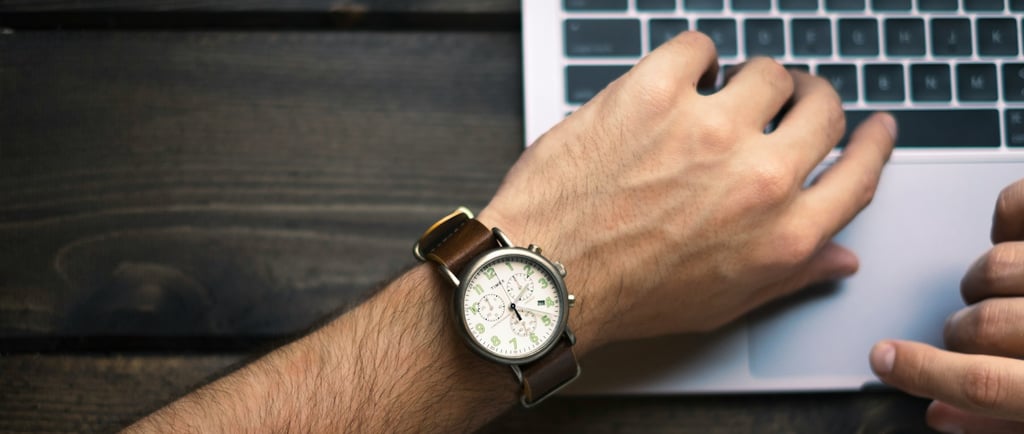 a man's wrist watch and a watch on a laptop