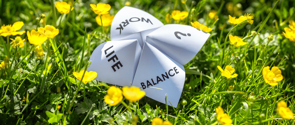 field of buttercups with a paper choice game, showing options work, life, balance, question mark