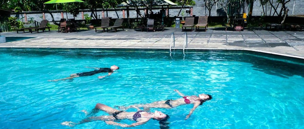 a woman swimming in a pool with two people for intro dive in bali