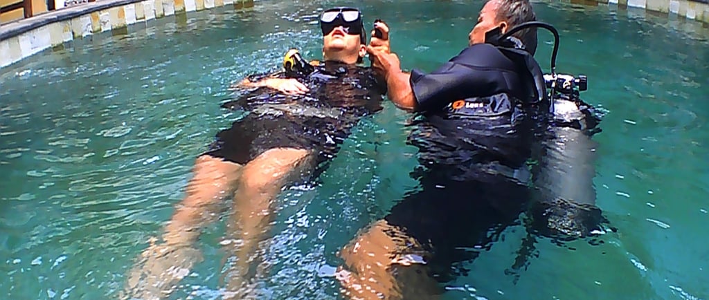 a man and woman in scuba gear in a pool