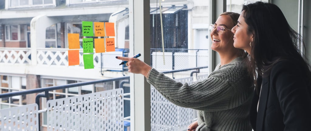 duas-mulheres-conversando-em-frente-à-uma-janela-com-post-its-colados