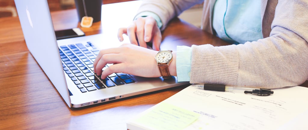 mulher-estudando-no=computador-com-livros-celular-e-chá-à-mesa