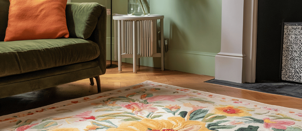 big colorful floral rug paired with green velvet sofa in a room full of soft green pallettes
