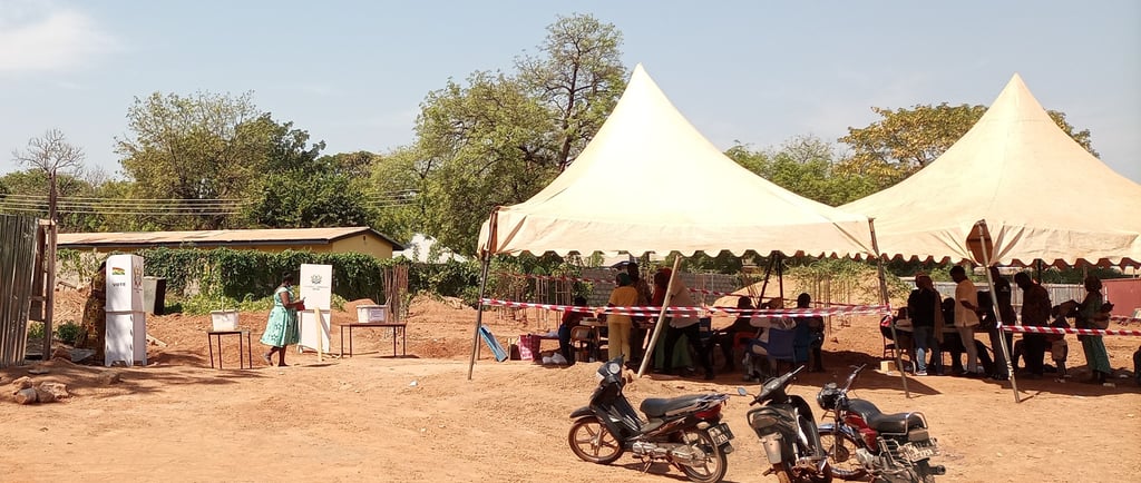 a group of eligible Ghana's standing around a tent casting their vot