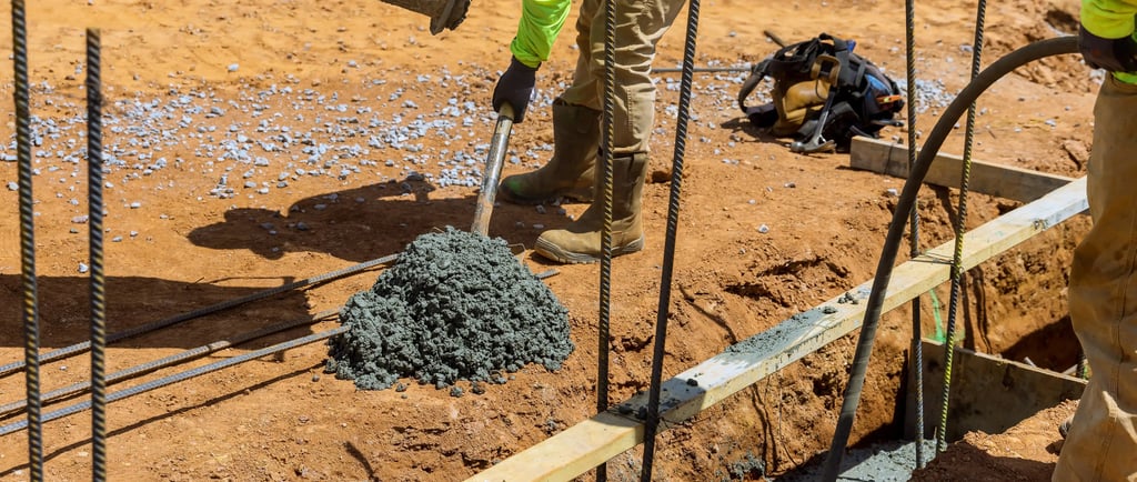 a man in a yellow jacket is pouring concrete into a concrete slab