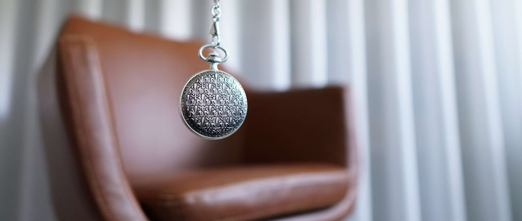 a silver locket with a silver chain in front of a chair