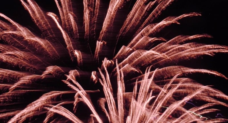 reddish pink fireworks exploding against a black background