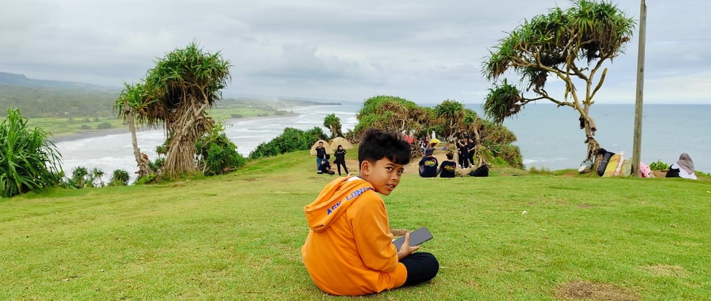 a man sitting on a hill with a handphone