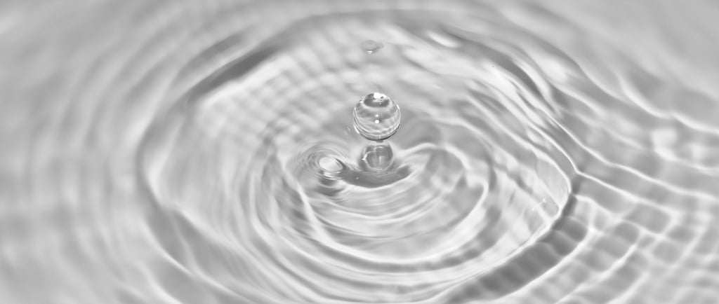 Water droplet creating gentle ripples in clean water, symbolizing purity and sustainable washing.