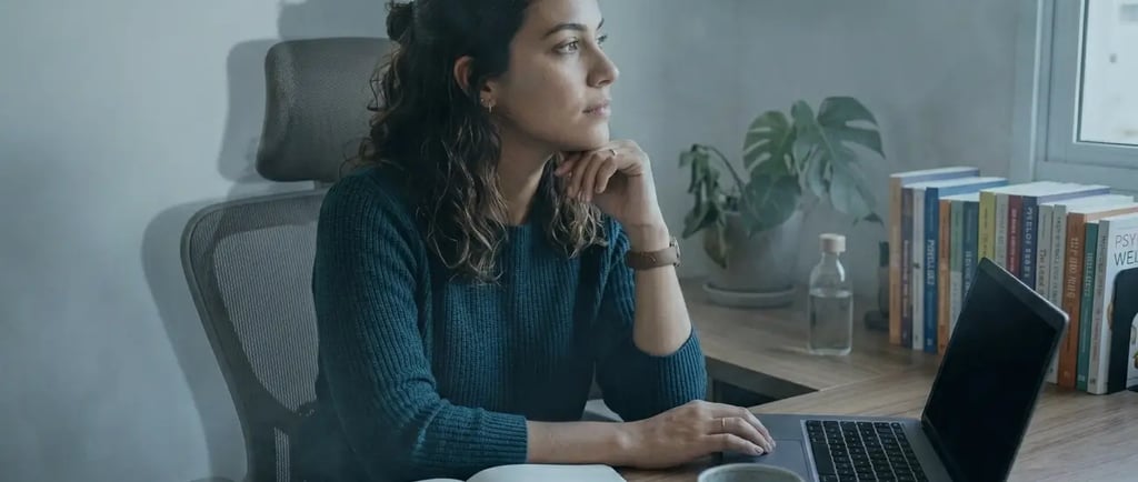 Uma mulher pensativa trabalhando remotamente em uma mesa de escritório em casa, com um laptop