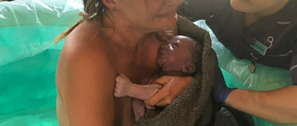 A mother holding her newborn baby after a successful waterbirth with the support of a midwife.