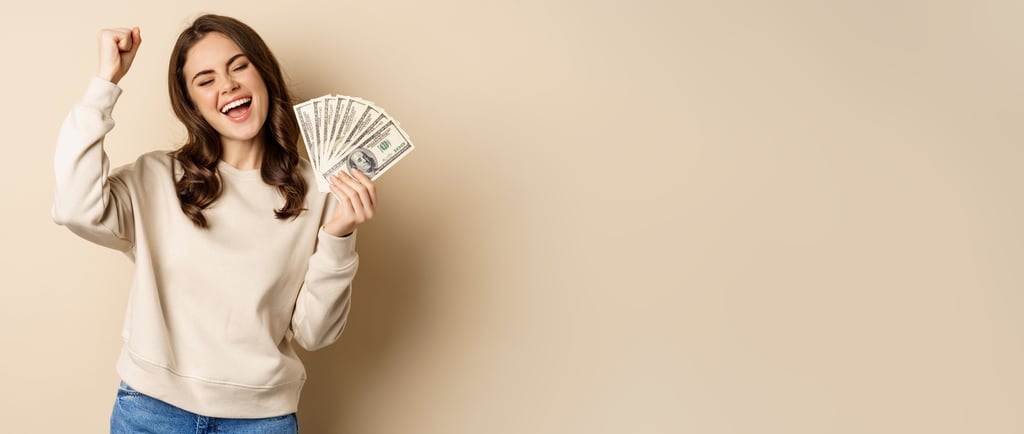 A happy woman cheering and holding a fan of hundred dollar bills representing financial success and cash earnings.