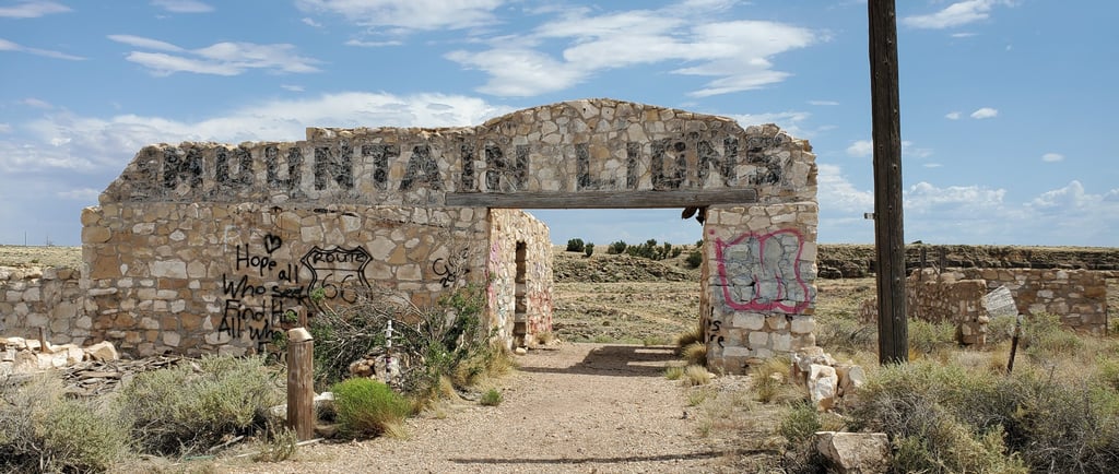 Abandoned stone building ruins with Mountain Lions sign and graffiti at Two Guns on Route 66.
