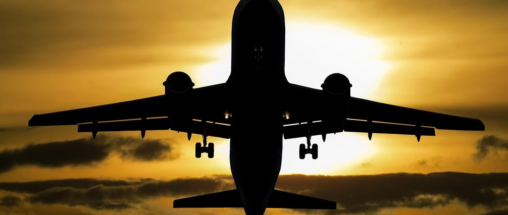 a plane flying in the sky at sunset