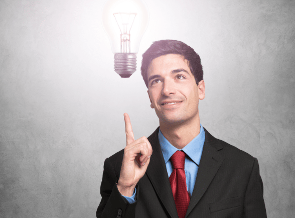a man in a suit and tie is pointing at a light bulb
