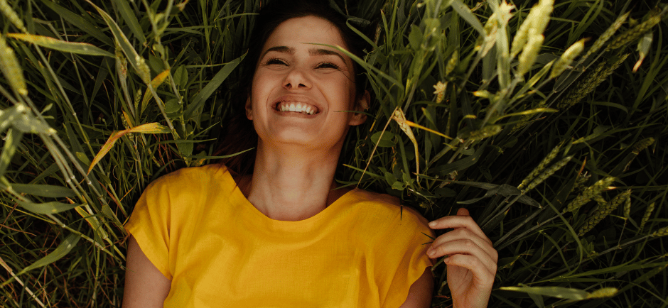 a woman in a yellow dress smiling and holding a flower