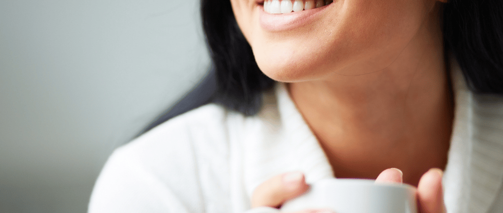 a woman holding a cup of coffee and smiling