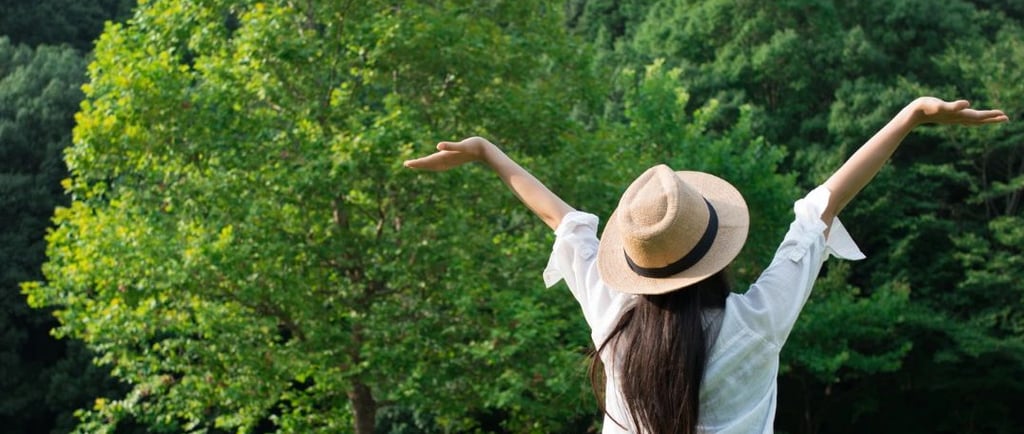 a woman sitting on the grass with her arms outstretched up