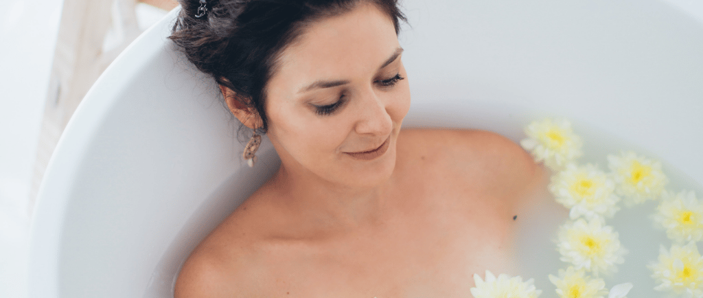 a woman in a bathtub with flowers in the tub